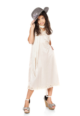 Pretty cute caucasian girl is playing dress up. She is wearing a beige dress, grey hat and high heel shoes.の写真素材