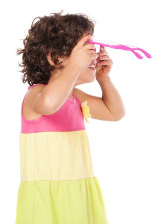 Adorable small caucasian child with curly hair wearing a pink blue and yellow dress. The girl and her father are playing with pink sunglasses.の写真素材