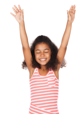 Adorable cute african child with afro hair wearing a white and pink striped dress. The girl is worshipping with her hands lifted up.の写真素材