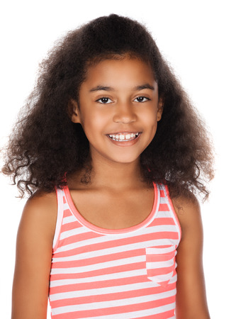 Adorable cute african child with afro hair wearing a white and pink striped dress. The girl is standing and smiling at the camera.の写真素材
