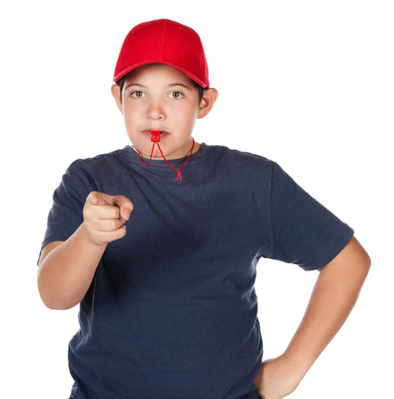 Young caucasian boy wearing a blue t-shirt and jeans and a red coach cap and whistle.の写真素材