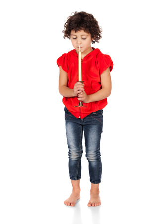 Adorable small caucasian child with curly hair wearing a bright red hooded top and blue jeans. The girl is holding a candle.の写真素材