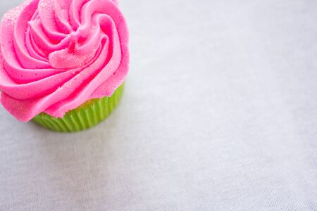 Single bright colorful cupcake on a white table cloth.の写真素材