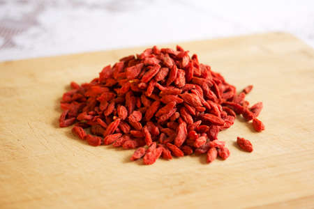 Pile of healthy red natural dried goji berries on a wooden chopping board.の写真素材