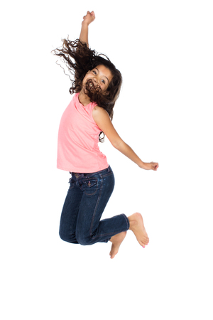 Pretty cute caucasian girl wearing a pink top and blue jeans. The girl is jumping and smiling.の写真素材