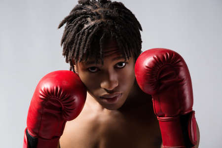 Young muscular athletic male boxer wearing blue boxing shorts and red boxing gloves. Fighter is on a grey background.の写真素材