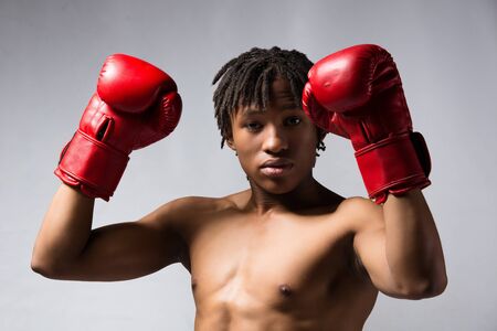 Young muscular athletic male boxer wearing blue boxing shorts and red boxing gloves. Fighter is on a grey background.の写真素材