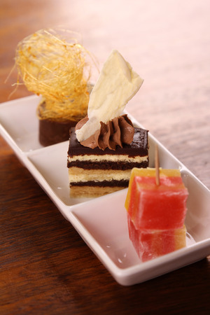 Three beautiful delicious gourmet desserts on a white plate. Chocolate layered cake, fudge, mousse and turkish delights.の写真素材