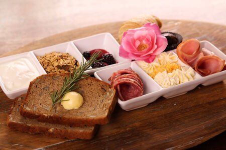 Full continental breakfast served on a wooden chopping board.の写真素材