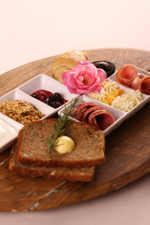 Full continental breakfast served on a wooden chopping board.の写真素材