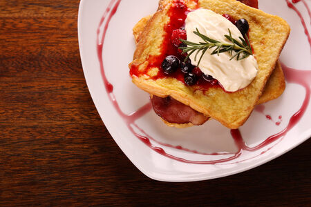 Delicious french toast with bacon syrup berries and cream on a white plate on a wooden table. Image contains copy space.の写真素材