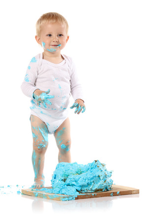 A one year old baby boy smashing a blue iced birthday cake on a wooden board. Image is isolated on a white background.の写真素材