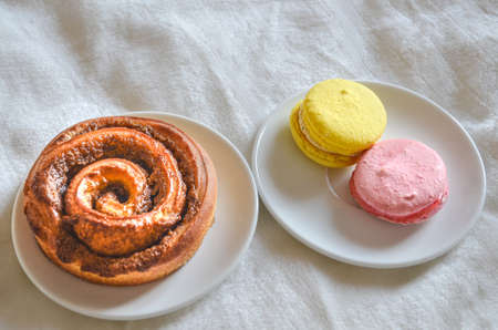 Cinnamon roll and Macarons "Strawberries and lemon flavour" on trayの写真素材