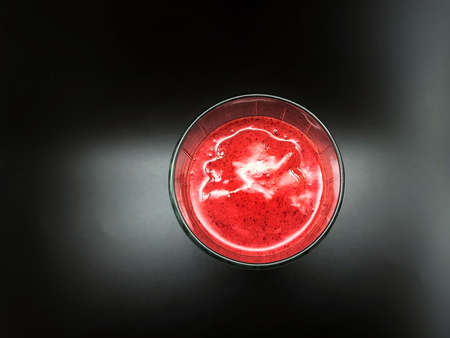 A glass of strawberry smoothie on a black background, top viewの写真素材
