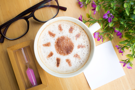 latte art coffee in sun design with papernote and sandglass on wooden  table, vintage toneの写真素材