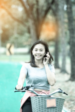 de-focused , Attractive woman taking with phone while ride bicycle in countryside road  , lifestyle concept , cool toneの写真素材