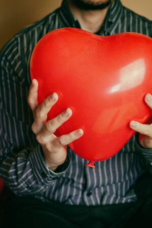 Young man holding a heart shaped balloonの写真素材