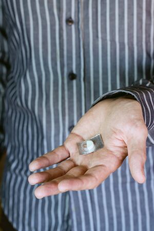 Young man hand holding a pill