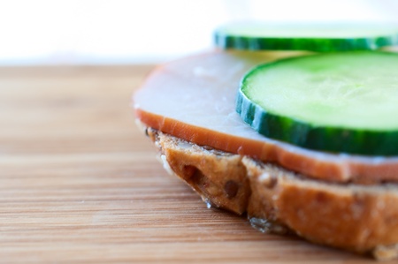 Sandwich with ham and cucumber on a wooden board close upの写真素材