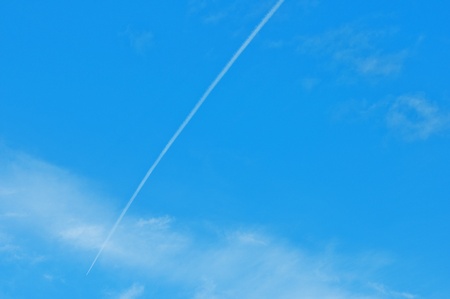 Trace of an airoplane on a cloudy blue skyの写真素材