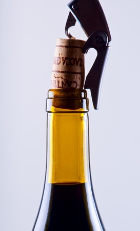 Corkscrew and wine stopper with a yellow bottle close upの写真素材