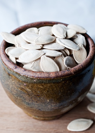 Ceramic bowl full of pumpkin seeds on kitchen tableの写真素材