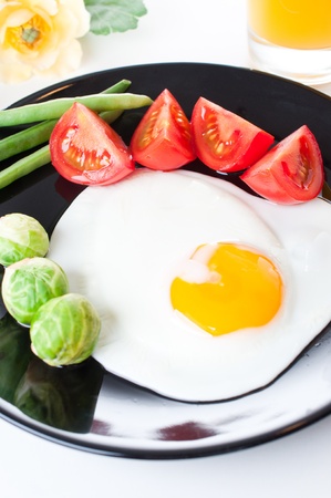 Fried egg with vegetables for breakfast on white backgroundの写真素材
