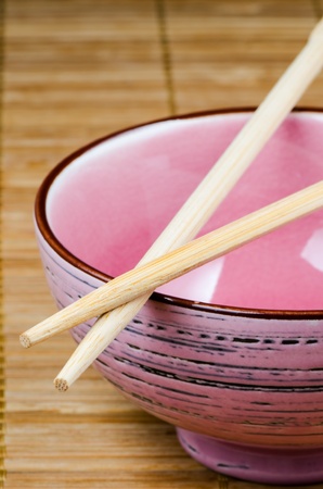 Empty pink rice bowl on bamboo matの写真素材