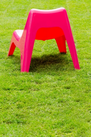 Red plastic chair on green grassの写真素材