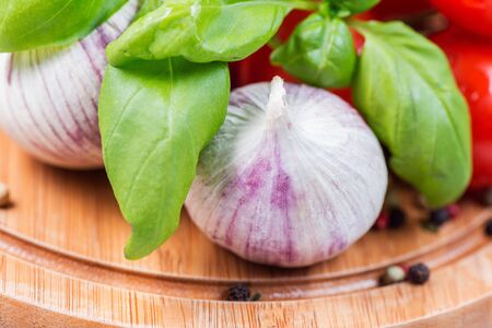 Fresh tomatoes, basil and garlic on wooden boardの写真素材