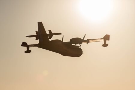 Firefighter airplane on sky and sun background
