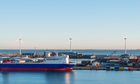Cargo freight ship with crane at shipyard and wind electric generators on backgroundのeditorial素材