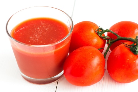 Tomato juice and tomatoes on white tableの写真素材
