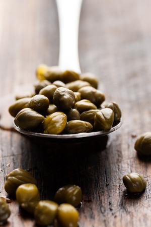 Pickled capers in spoon on wooden backgroundの写真素材