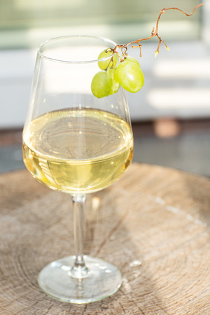 Glass of white wine with grapes on wooden surfaceの写真素材