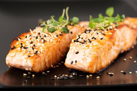 Grilled salmon, sesame seeds  and marjoram on a black plate. Studio shotの写真素材