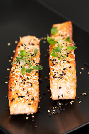 Grilled salmon, sesame seeds  and marjoram on a black plate. Studio shotの写真素材