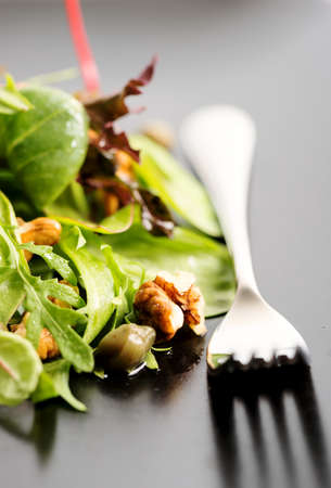 Fresh ecological salad mix with nuts on black plate, macroの写真素材