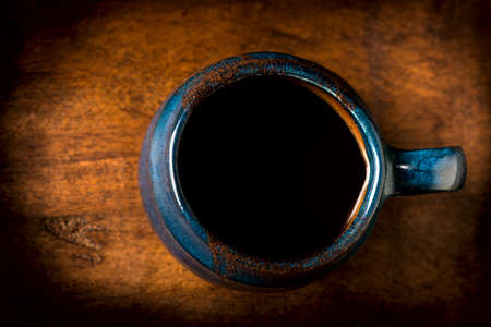 Coffee in grunge blue clay cup on rustic wooden backgroundの写真素材