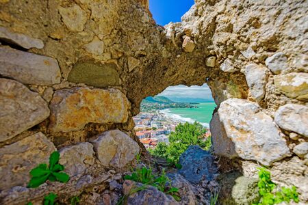 Aerial view of town Cefalu from above through hole in old stone wall, Sicily, Italyの写真素材