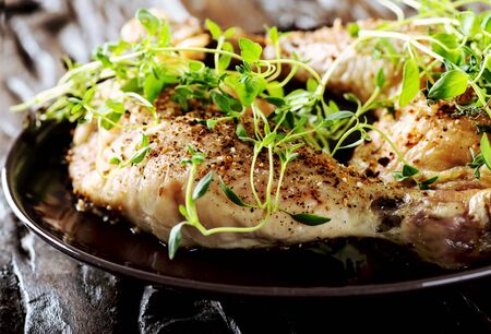 Grilled spicy chicken legs with herbs and spices on a black plateの写真素材