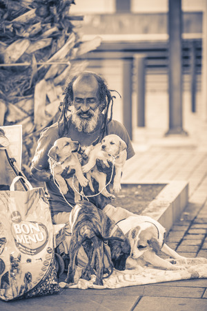 TENERIFE, SPAIN - MARCH 16, 2014: Homeless hobo sitting on a street with his dogs.It is estimated that there are around 40,000 homeless people in Spainのeditorial素材