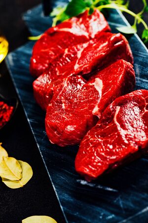 Beef steaks on cutting board with herbs and spices