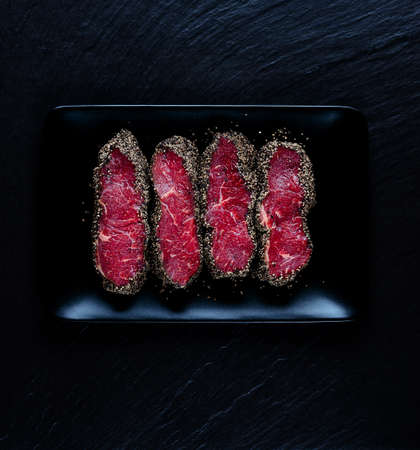 Pepper steaks on black stone plate top viewの写真素材