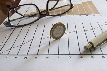 Stock chart with coin, pen and glassesの写真素材