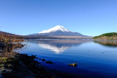 Landscape Fuji Mountain and Wooden Bridge with snow behind clear blue sky background and front a reflection in water lake.の写真素材
