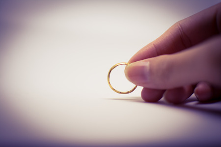 The golden ring held in woman's hand is the variable one. It is from her beloved person. on blurred purple background.の写真素材