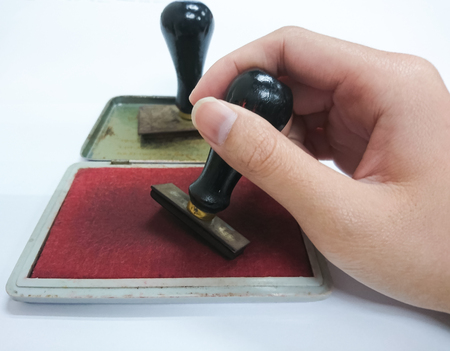 Woman's hand holding the rubber stamp isolated on white backgroundの写真素材