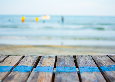 The old wooden table placed beside the beach. There is a blue line on the table. Behind the table is...