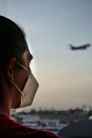 man looking outside while airplane passes through the skyの写真素材